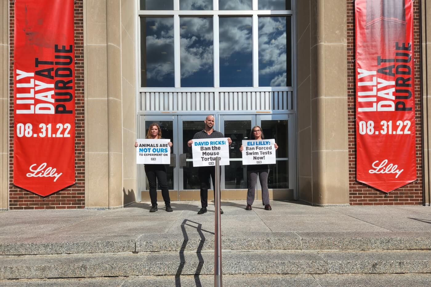 PETA supporters stand outside the Lilly Day at Purdue event with protest signs against the forced swim test