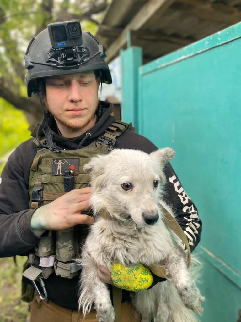 Person in military gear holding dog