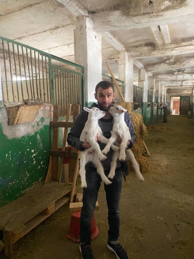 A man holding two baby goats