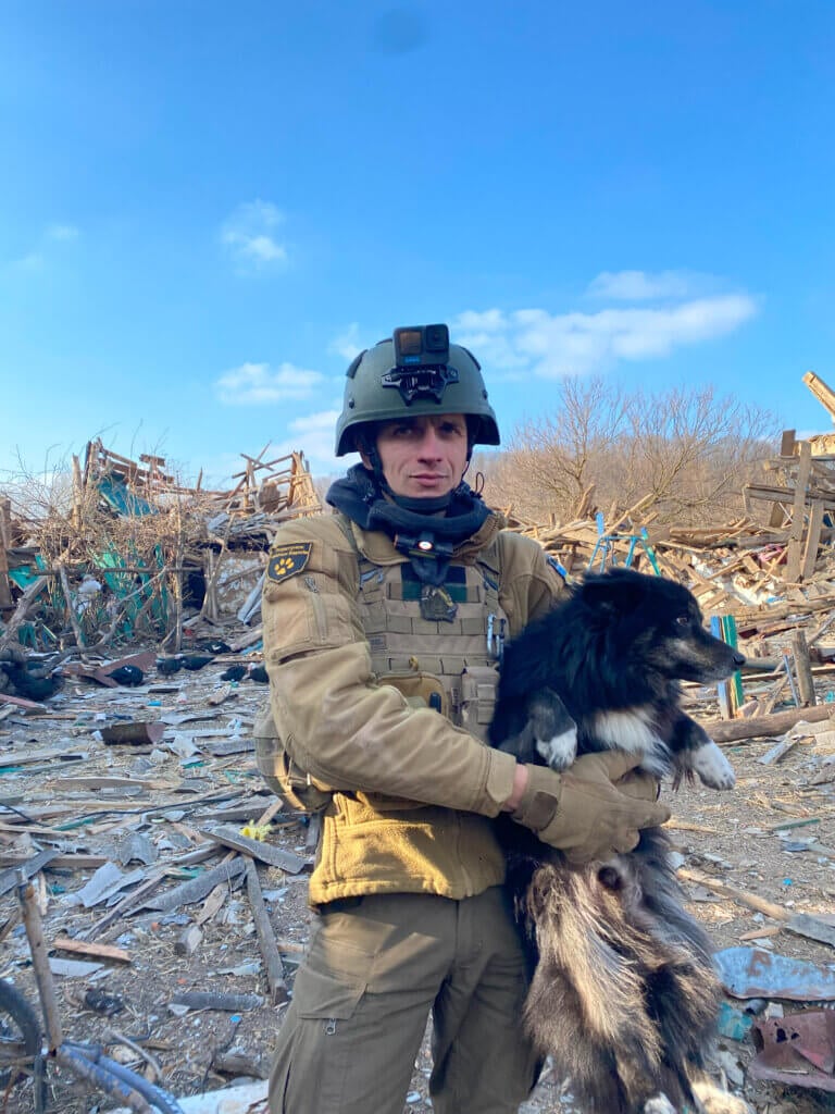 ARK member holds a dog in front of rubble