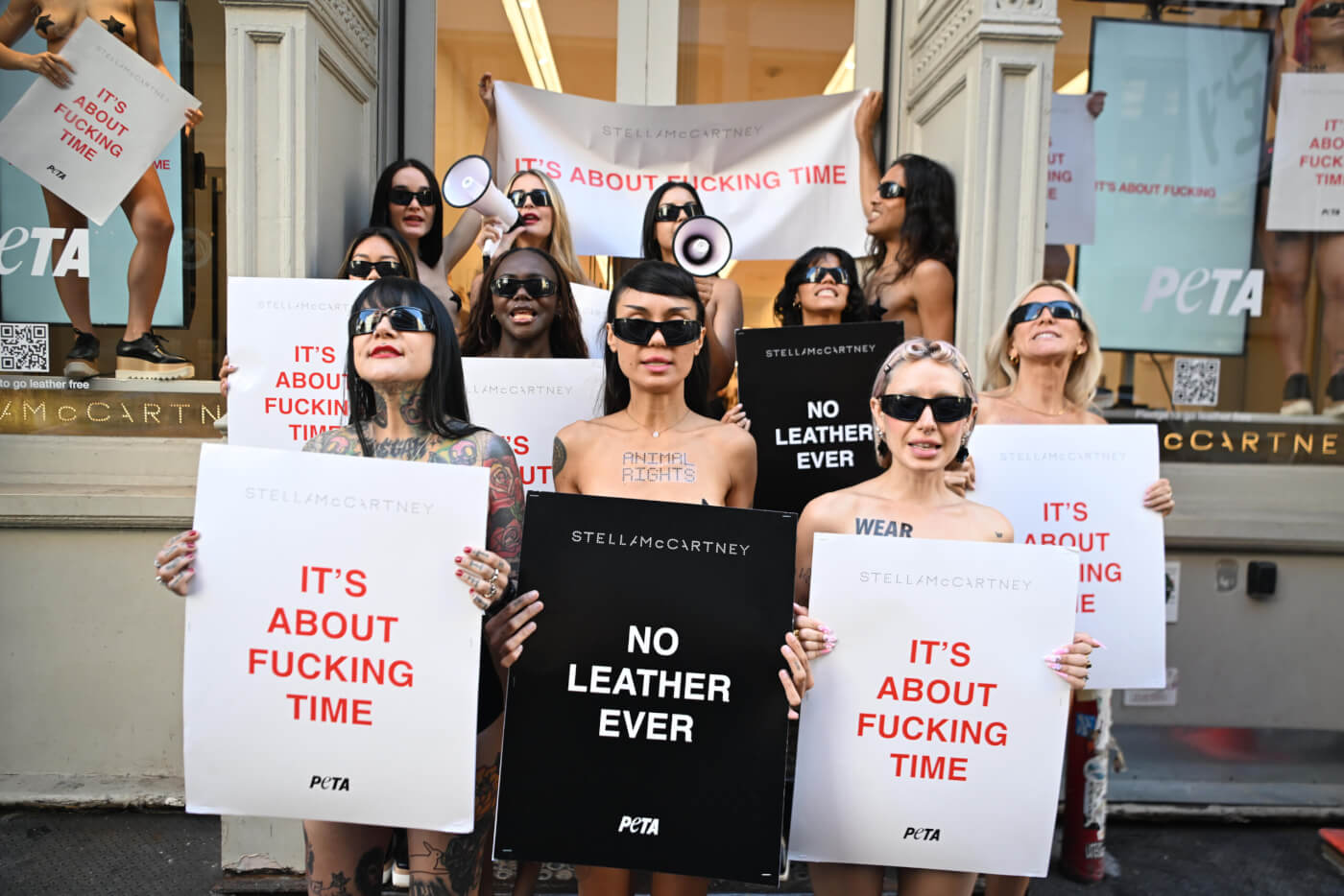 activists outside stella mccartney store in new york holding "its about fucking time" signs