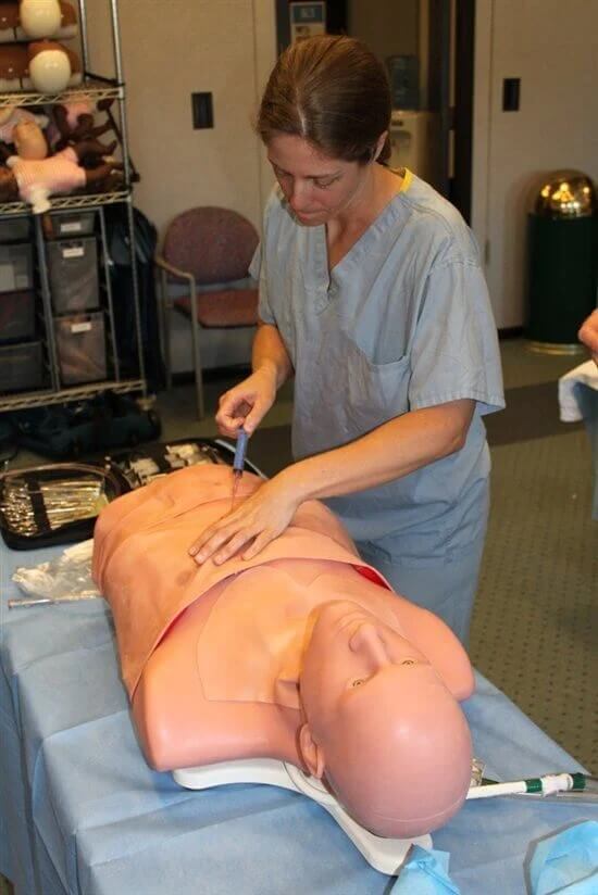 A person in scrubs putting a scalpel to a traumaman