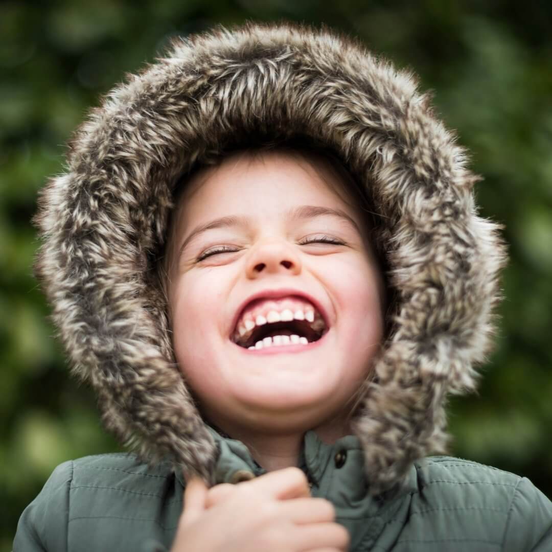 happy child laughing wearing a winter coat 