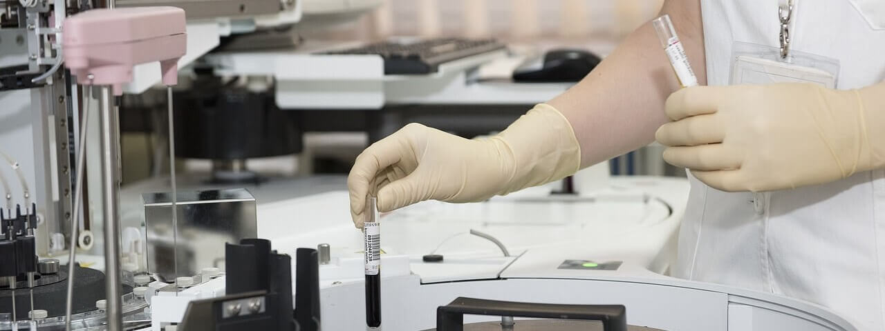 A person wearing gloves using a centrifuge