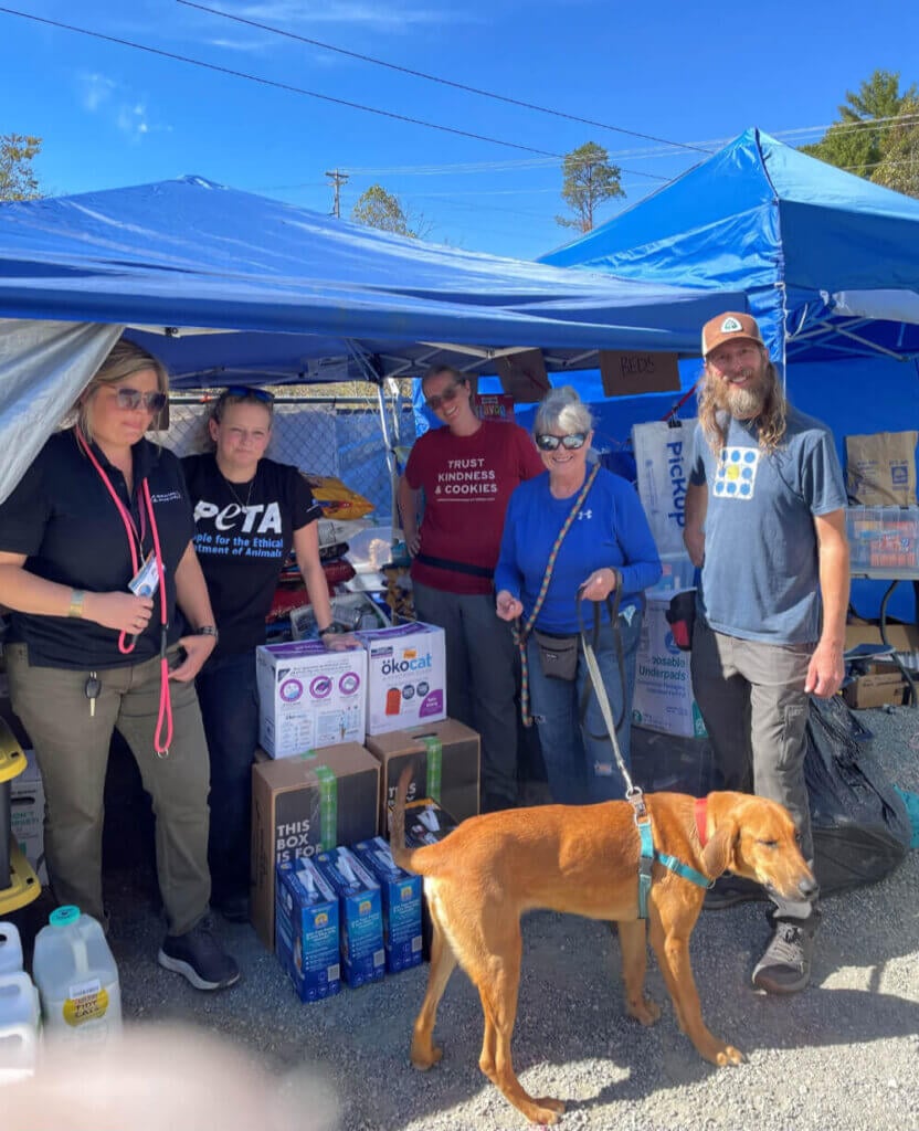 Group of residents and PETA workers in a photo with a brown dog in the foreground 