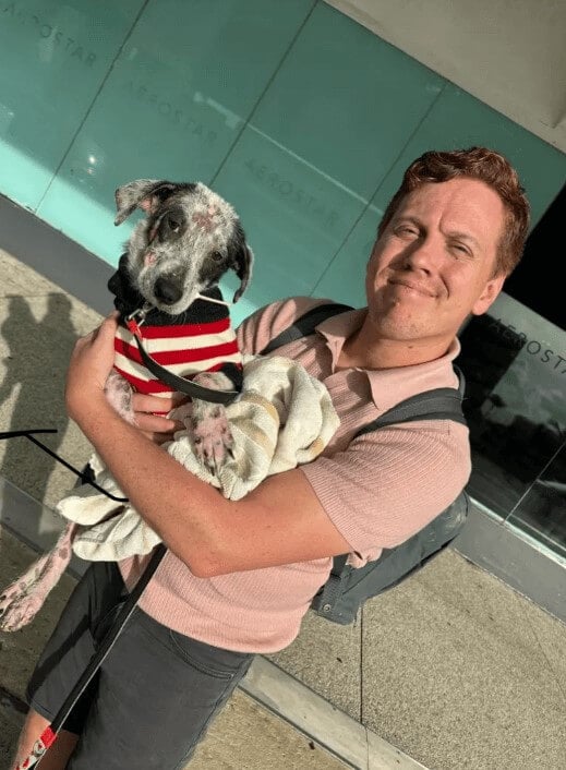 A man holding up Minnie, a black and white dog