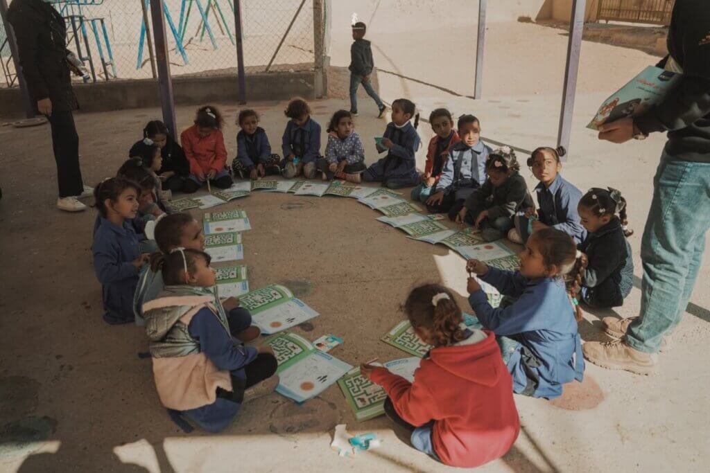 Children sitting in a circle with activity books