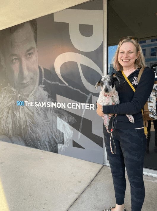 A woman holding up Minnie in front of PETA's Sam Simon Center