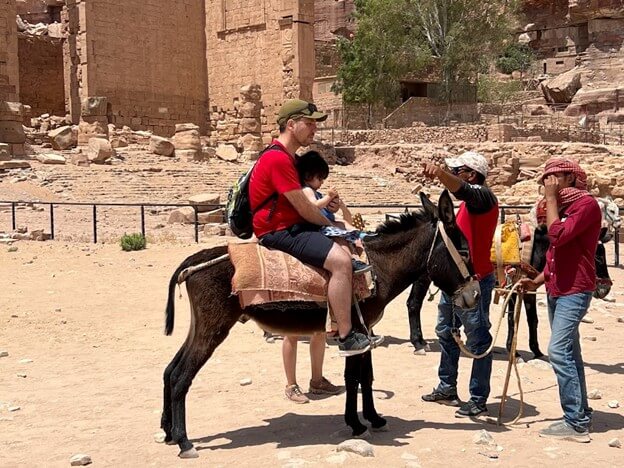 tourists ride donkey in petra jordan